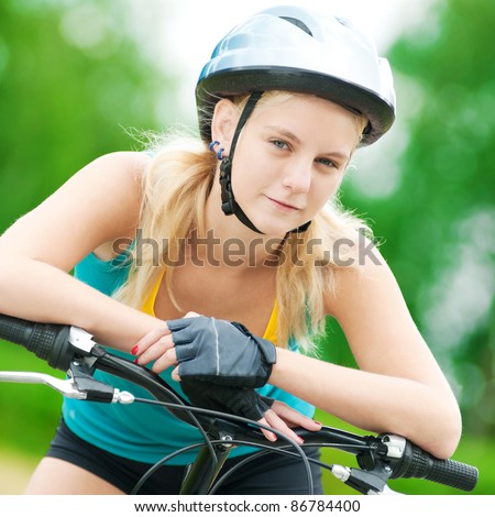 Portrait of pretty young woman with bicycle in a park - outdoor