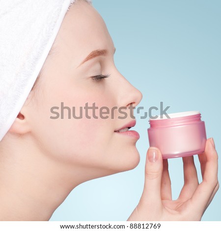 Beautiful woman smell jar of moisturizer cream. Close-up fresh young woman face