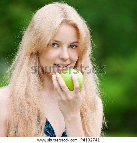 Portrait of a young beautiful woman with green apple at park