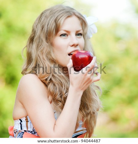 Portrait of a young beautiful woman with red apple at park