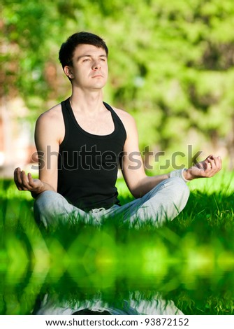 A young man doing yoga in the green park