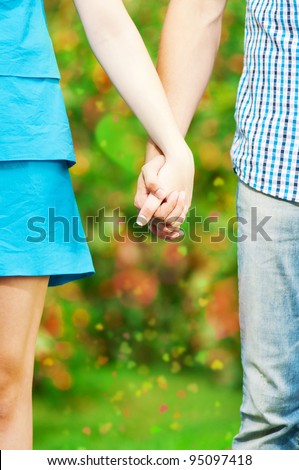 Concept shot of friendship and love of man and woman: two hands over green nature park