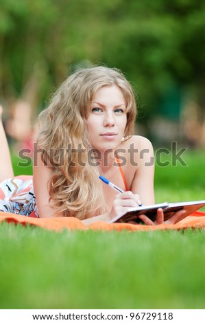 Beautiful young woman study at green summer park