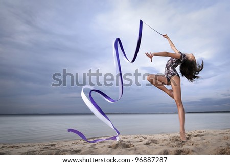 young professional gymnast woman dance with ribbon - outdoor sand beach