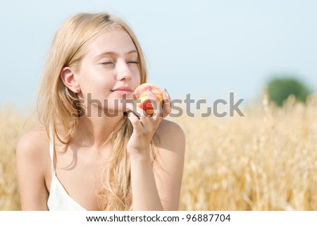 Young happy woman in wheat field with peach. Summer picnic