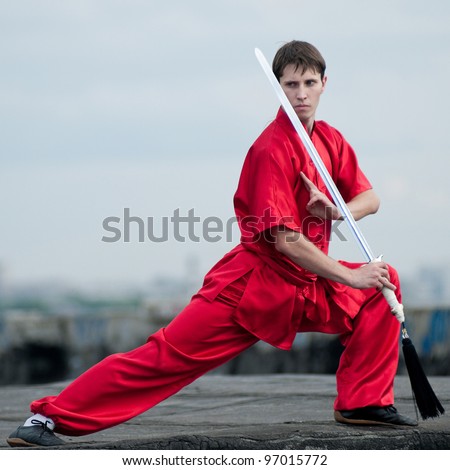 Shaolin warriors wushoo man in red with sword practice martial art outdoor. Kung fu
