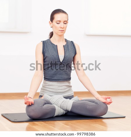 Beautiful sport woman doing stretching fitness exercise at sport gym. Yoga lotus pose