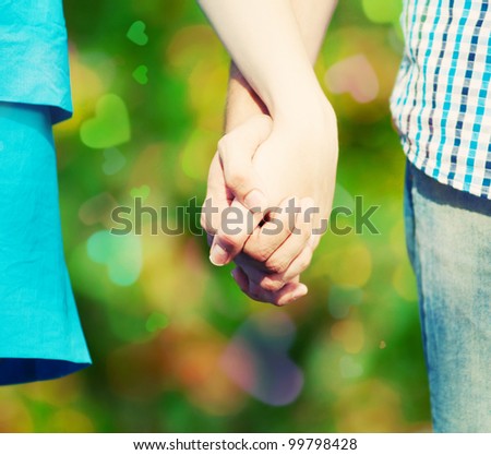 Concept shot of friendship and love of man and woman: two hands over green nature park