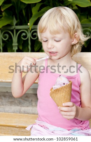 little girl with ice cream sitting on bench