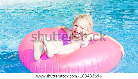 little girl with rubber ring in swimming pool