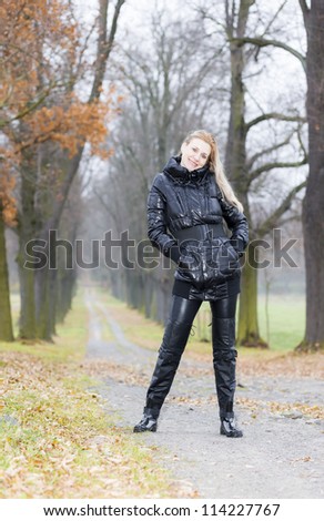 woman wearing black clothes and boots in autumnal alley