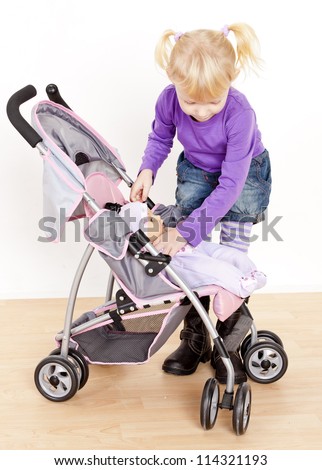 little girl playing with a doll and a stroller