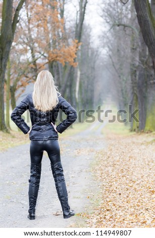 woman wearing black clothes and boots in autumnal alley
