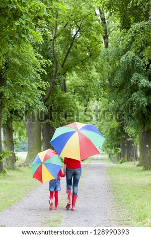 mother and her daughter with umbrellas in spring alley mother and her daughter with umbrellas in spring alley
