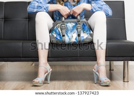 detail of woman wearing summer shoes with a handbag sitting on sofa