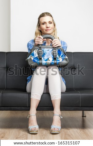woman wearing summer shoes with a handbag sitting on sofa