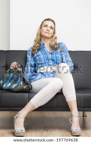 woman wearing summer shoes with a handbag sitting on sofa