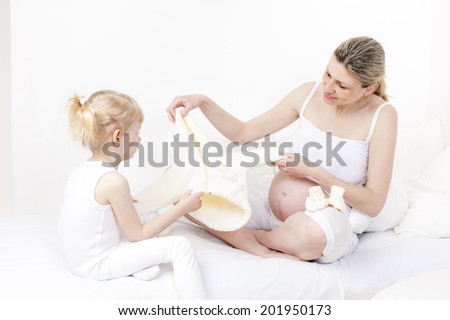 little girl and her pregnant mother with clothes and shoes for a baby