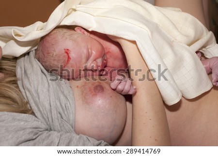 laying of a newborn baby to the breast after birth