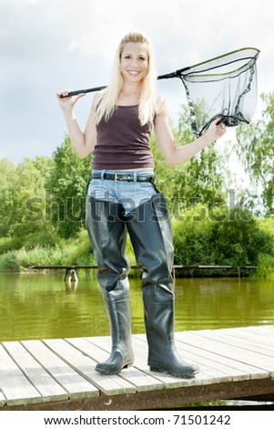 fishing woman with landing net standing on pier