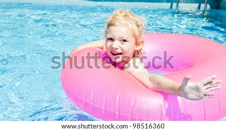 little girl with rubber ring in swimming pool