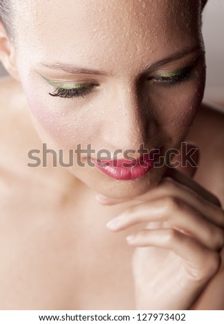 Gorgeous woman with water drops on face looking down