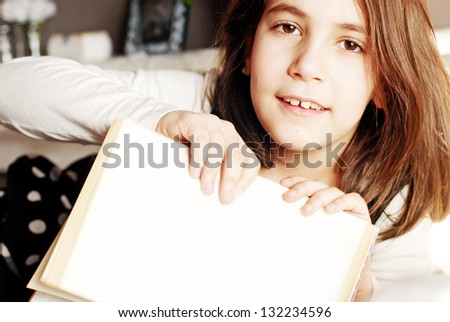 Little girl pointing with finger on blank book with copy space