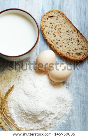 milk, bread, eggs, flour and wheat on a vintage wooden background