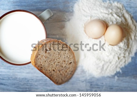 milk, bread, eggs, flour and wheat on a vintage wooden background