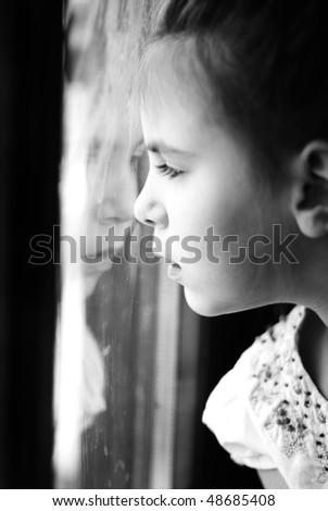 Little girl looking through window with reflections