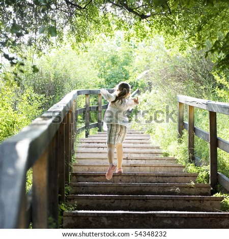 young girl in the forest running up stairs