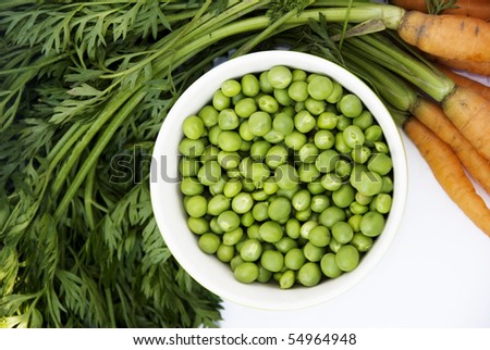 green peas in small white bowl with carrots
