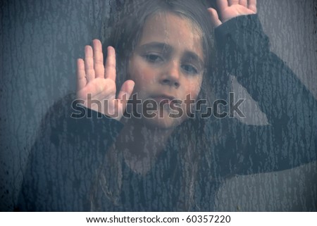 little girl behind a rain-splattered window