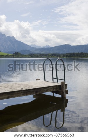 end of a pier with a small step leading into a mountain lake