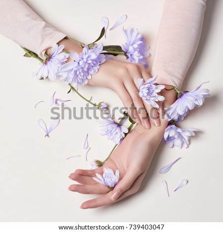 Fashion art skin care of hands and blue flowers in hands of women. Creative beauty photo hands, sitting at table on a contrasting pink background with colored shadows. Cosmetics for hands anti wrinkle