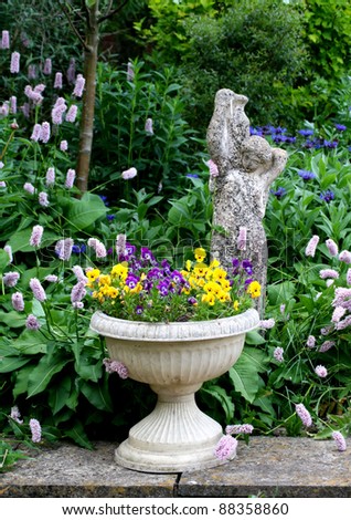 Stone Flower container with pansies and a stone statue