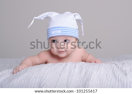 Portrait of a cute little baby boy with a cap lying on front