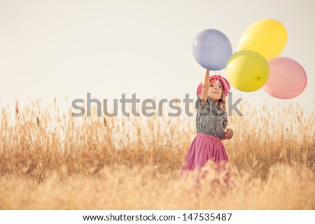 Little Girl Playing With Balloons On Wheat Field