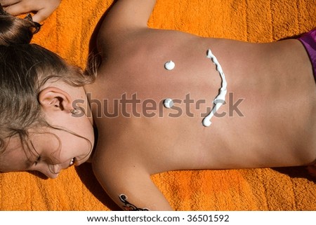Funny face from cream for a sunburn on the back for a young girl