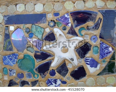 Starfish mosaic made with objects found on a beach embedded in sand