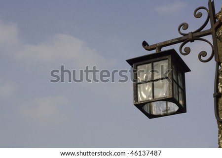 Old cast iron lantern hanging on the outside of a building against a blue sky. Copy space for text