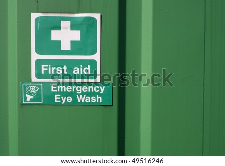 Green first aid and emergency eye wash signs on a green background with copyspace