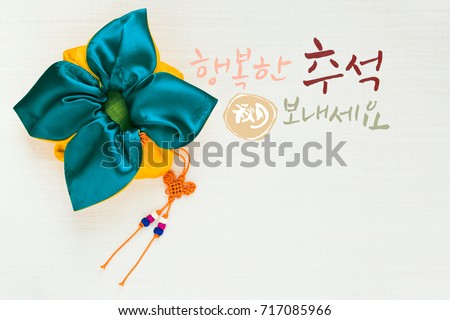 \'Happy Chuseok & Hangawi, Translation of Korean Text : Happy Korean Thanksgiving Day\' calligraphy and Korean traditional bag & knot background of white ramie fabric.