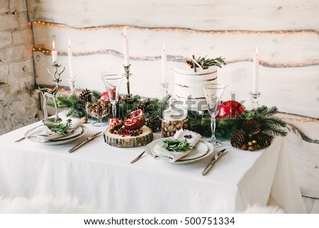 A neat and cozy table for two in christmas decorations, wooden wall with yellow lights on the background