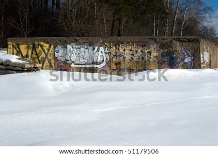 Graffiti-covered abandoned concrete construction in early spring Gulf of Finland beach
