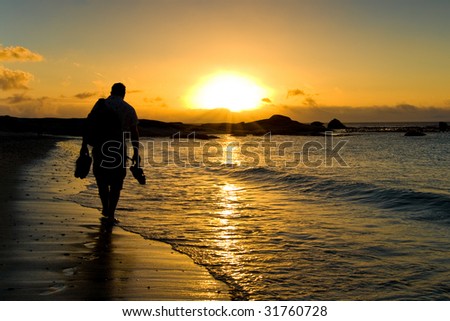 In a sunset scene a man walk on the beach just beside Cape Town, South Africa.