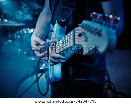 Performance of the rock band. The guitarist plays solo. The bass player plays solo. Drummer. Bass drum. Close-up.