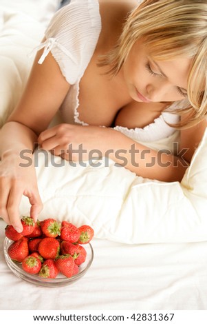 Woman eating strawberry lying on stomach