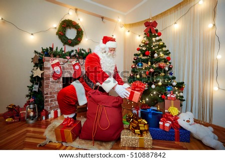 Santa Claus gets gifts from the bag and put them under the tree on Christmas.