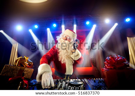 DJ Santa Claus mixing up some Christmas event.  Disco light around fun, colorful atmosphere. Musical New Year.